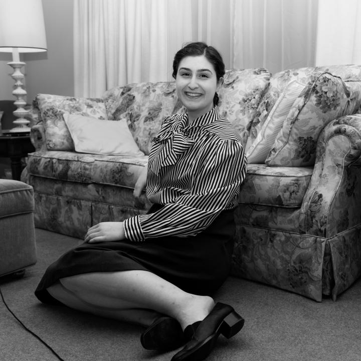 A woman sitting on the floor in front of a couch.