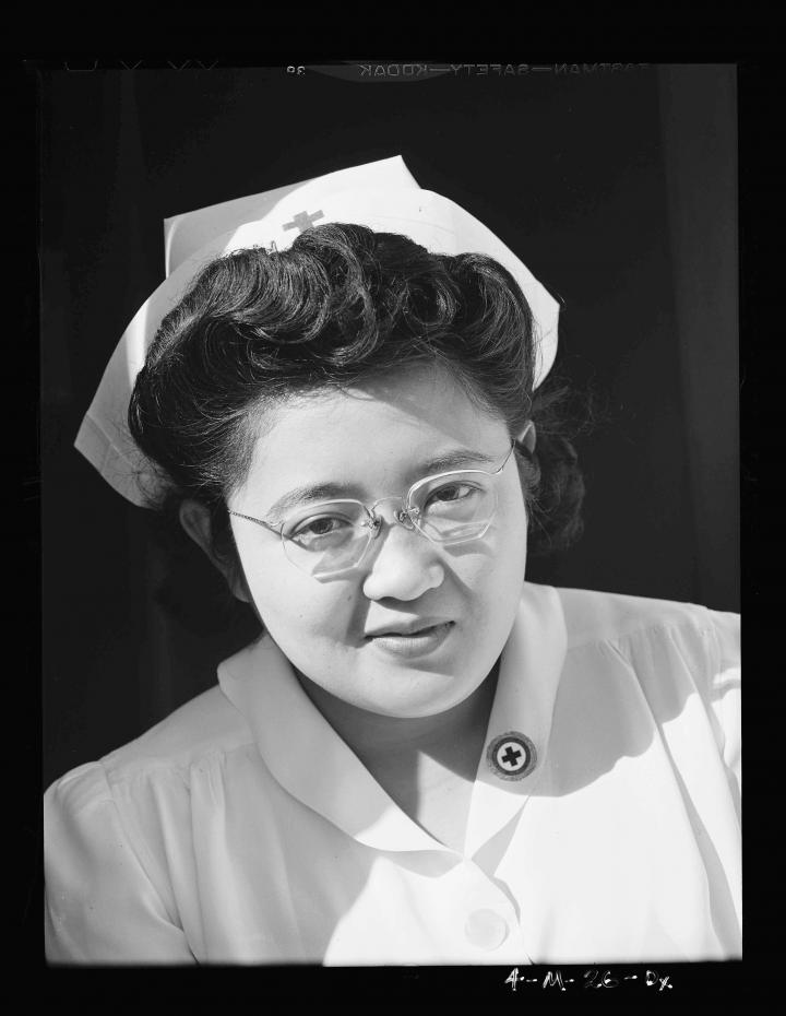 The profile of a nurse with glasses from the chest up. 
