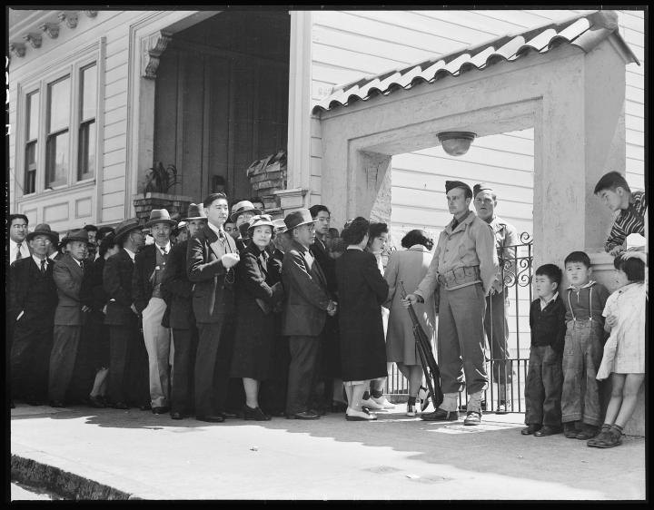 A long line of Japanese Americans entering an internment camp. 