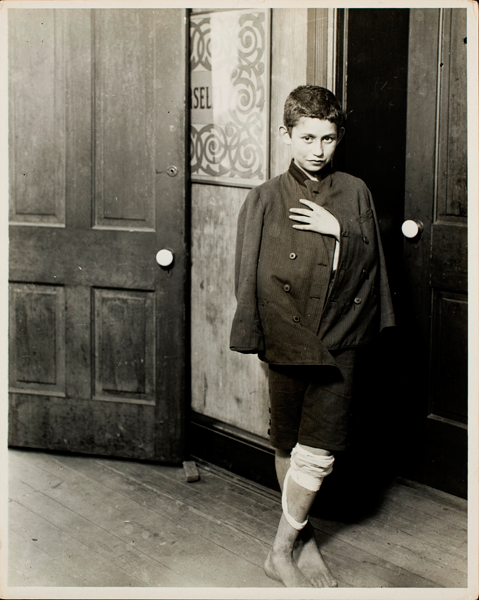 A young boy leaning against a door. 
