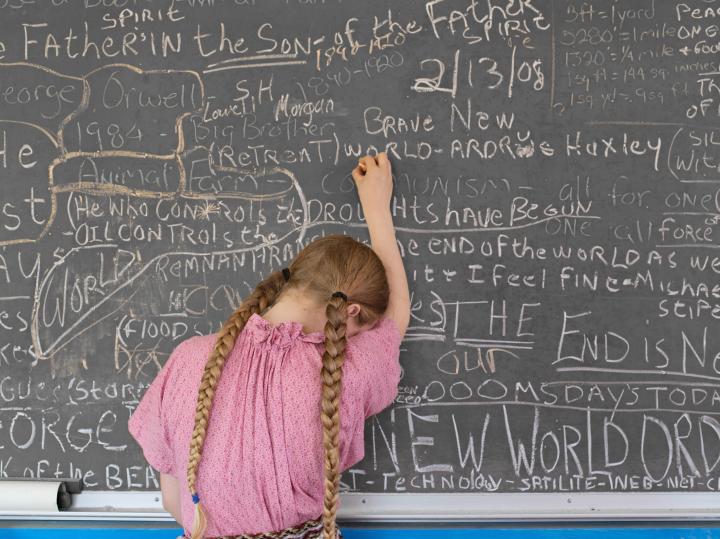 A little girl writing on the chalkboard